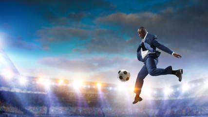 Fototapeta na wymiar Black businessman in a suit playing footbal