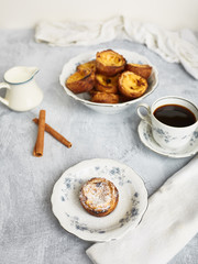 Fresh baked Portuguese Egg Custard Tarts, Pasteis De Nata, served on a vintage porcelain plate with a cup of hot coffee. 