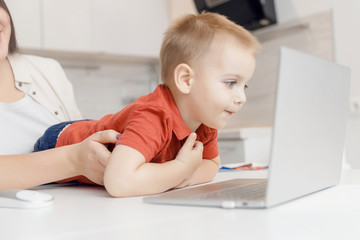 Boy child enthusiastically watching video blog or cartoons on laptop screen. Concept myopia,...