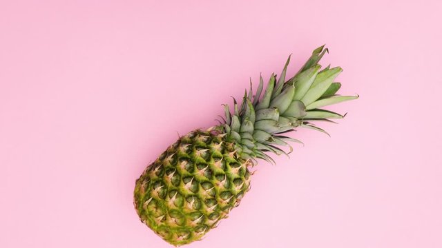 Pineapple passing on pink background - Stop motion 