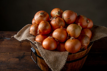 Fresh ripe onions in wooden bucket.