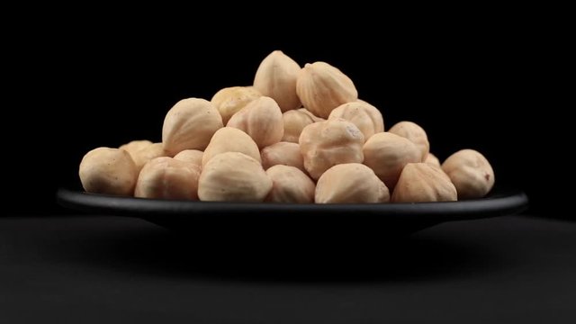 Hazelnut grains of spin around themselves on a black background and ground