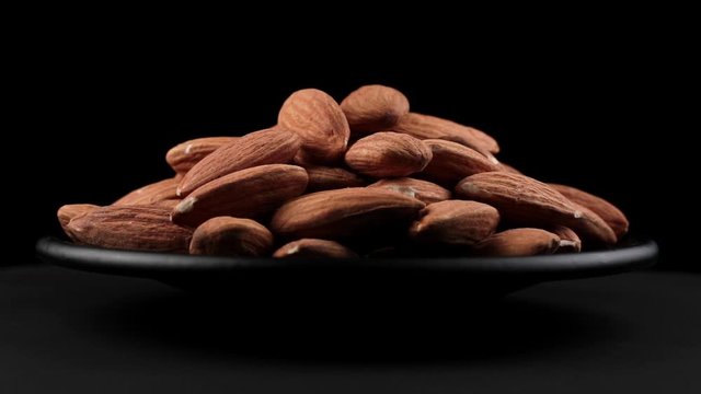 Almond grains of spin around themselves on a black background and ground