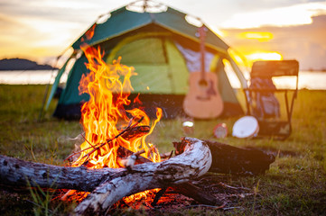 Camping bonfire surrounded by team of asian climbers hiker, they are playing music together in the forest path autumn season. Hiking, hiker, team, forest, camping , activity concept. - obrazy, fototapety, plakaty