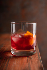 Red traditional old fashioned cocktail with orange zest on the rustic background. Selective focus. Shallow depth of field.