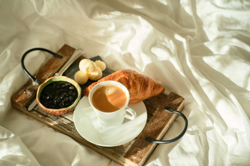 top view of Breakfast in bed with freshly baked croissants with jam and coffee on a wooden tray