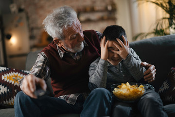 Grandfather and grandson watching television. Grandfather and grandson enjoying at home.	