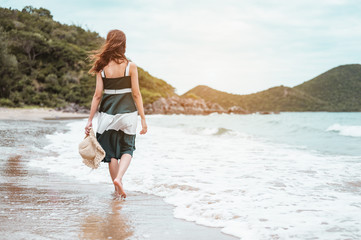 Fototapeta premium Happy asian women with holding hat walking barefoot to receive the wind and enjoy life on the beach vacation. beach, summer, liftstyle, positive mood, travel, relax concept.