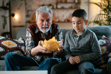 Grandfather and grandson watching television. Grandfather and grandson enjoying at home.	