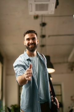 Businessman giving a handshake in office. Handsome man at work.	