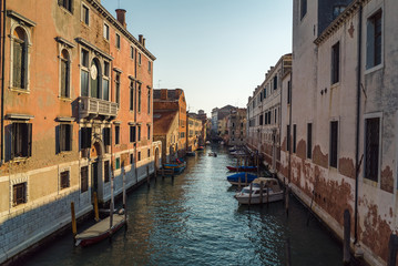 A scenic view of a beautiful Venetian canal on a warm sunny day with colourful houses and architecture running along the water in the town of Venice, Italy