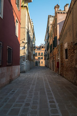 Fototapeta na wymiar Looking down an old Venetian alleyway between two old buildings in the town of Venice in Italy