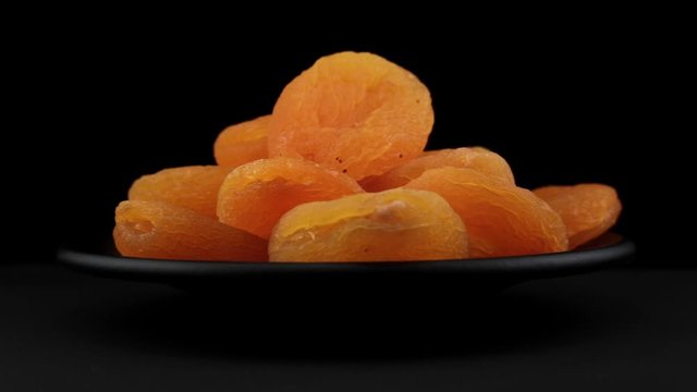 Dried apricot grains of spin around themselves on a black background and ground