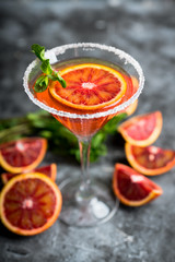 Red cocktail with bloody oranges in martini glass on the rustic background. Selective focus. Shallow depth of field.