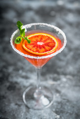 Red cocktail with bloody oranges in martini glass on the rustic background. Selective focus. Shallow depth of field.