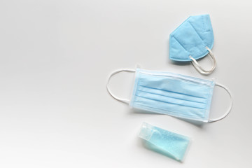 Face mask and alcohol gel on white background