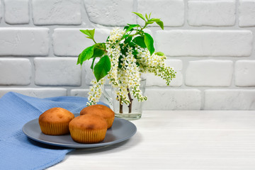 Cupcakes with a bouquet of white flowers. Cupcakes on a plate with a blue tablecloth and a bouquet...