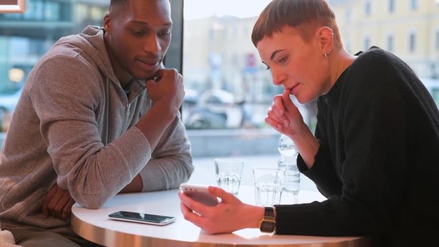 Young couple using smartphone in a cafe