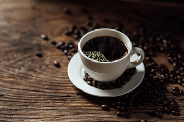 Hot black coffee cup and coffee beans on wooden background with natural light in the morning