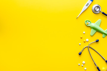 Kids - flu treatment. Pills, thermometer, stethoscope and toys on yellow background top view copy space