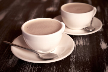 Two cups of coffee on a wooden table.