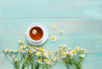 chamomile flowers and cup of tea on wooden table. summer teatime, romantic breakfast. copy space