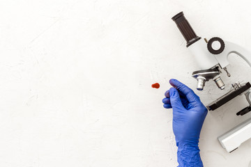 Clinical science research with microscope. Hand holds blood sample on white background top view...