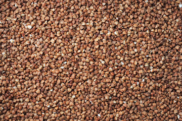 The texture of raw buckwheat groats. Background cereals buckwheat brown natural. Close up.