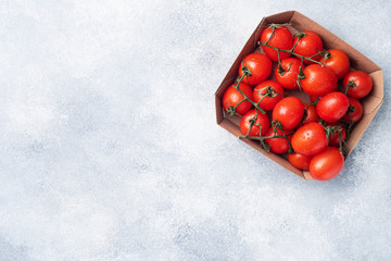 Ripe fresh cherry tomatoes on a branch in a cardboard package. Copy space.