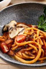 Pichi with mushrooms and creamy tomato allione in gray bowl