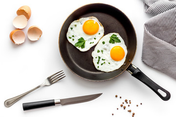 Fried eggs on frying pan on white background top view
