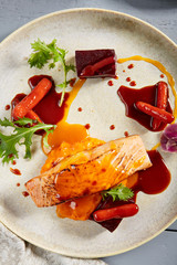 Salmon fillet with beet in herbs and passion fruit sauce close up