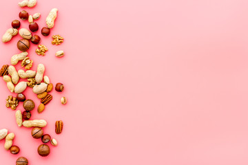 Nuts background - healthy snacks concept - on pink table top-down frame copy space
