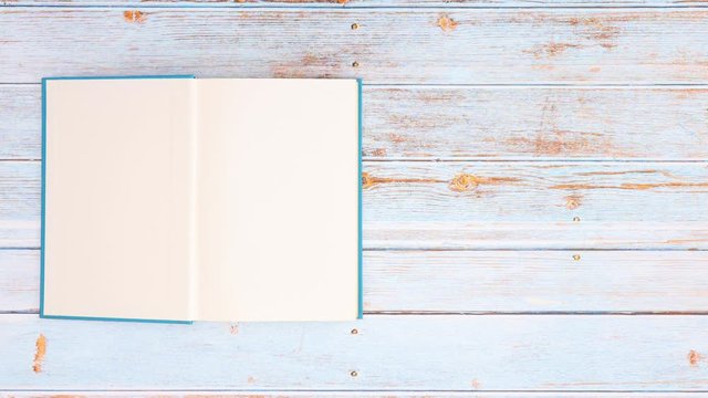 Blue book appear on wooden table and opens - Stop motion 