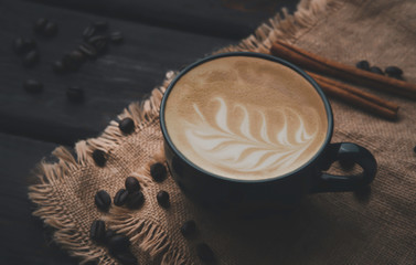 closeup latte coffee in a black coffee cup on dark grey wooden home kitchen table background