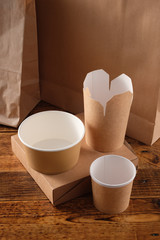 Street fast food paper cups, plates and containers. Eco-friendly food packaging on wooden background. Carering of nature and recycling concept.