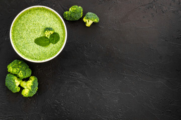 Green vegetable cream soup - broccoli - on black kitchen table top view copy space