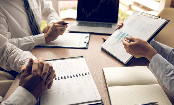Group of usiness partnership coworkers working to chart company financial statements report and profits work progress and planning in office room.