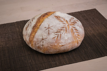 Home made traditional loaf of bread in slovenia with carved images of leaves and grain wheat on the crust. Festive bread with ornamental decorations.