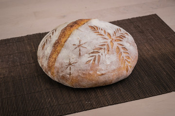 Home made traditional loaf of bread in slovenia with carved images of leaves and grain wheat on the...