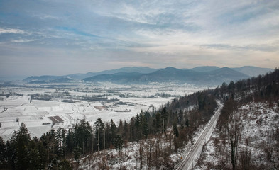 Fototapeta na wymiar Winter panorama over white plains and fields of southern ljubljana marshes and with clouds, with mountains and dense clouds in the background. Picture taken close to Verd and Borovnica village.