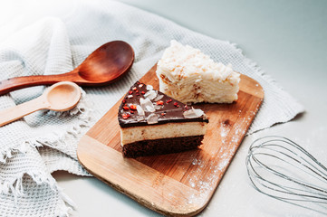 Chocolate beautiful cake and pancake cake on a wooden stand on the kitchen light table with a whisk, wooden spoons and a waffle towel. Homemade beautiful Breakfast