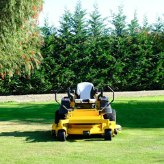Lawn mower park by green grass field, zero turn Lawn mower.
