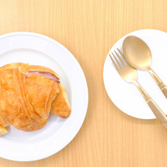 Croissant on white plate on wooden rustic background. the view from the top