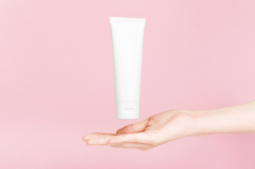 Female hand holding flacon for cream with golden cap. Plastic flacon for body lotion, toiletry. Container for cosmetics product. Skincare, advertising concept. Mockup style. Isolated on pink