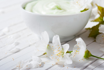 Obraz na płótnie Canvas moisturizer cream with cherry blossom on white wooden table background