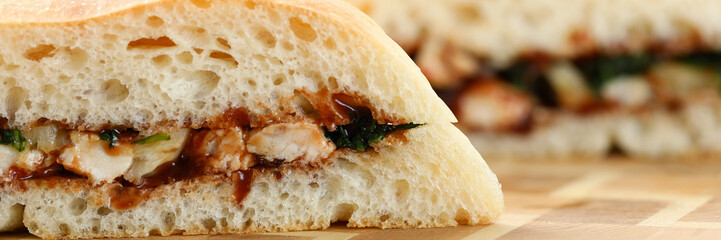 Cut chiken sandwich with ketchup against kitchen closeup background.