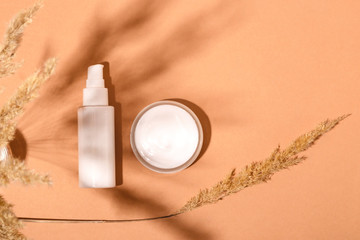 Fototapeta na wymiar Beauty care products close to nature on natural colored background with shadows of dried flowers.