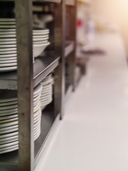 Rack with white plates cups in a small office canteen, Selective focus, sun flare.