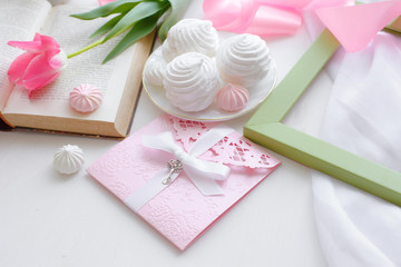 postcard good morning. Still life : a Cup of tea, a bouquet of pink tulips, a marshmallow book on a light background near the window.
